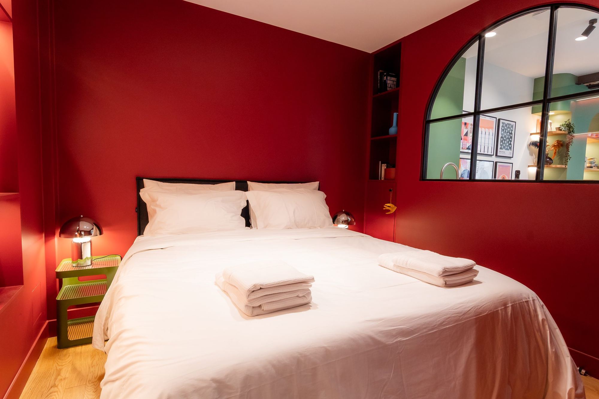 La suite : lit fait au carré, murs bordeaux, verrière en arche